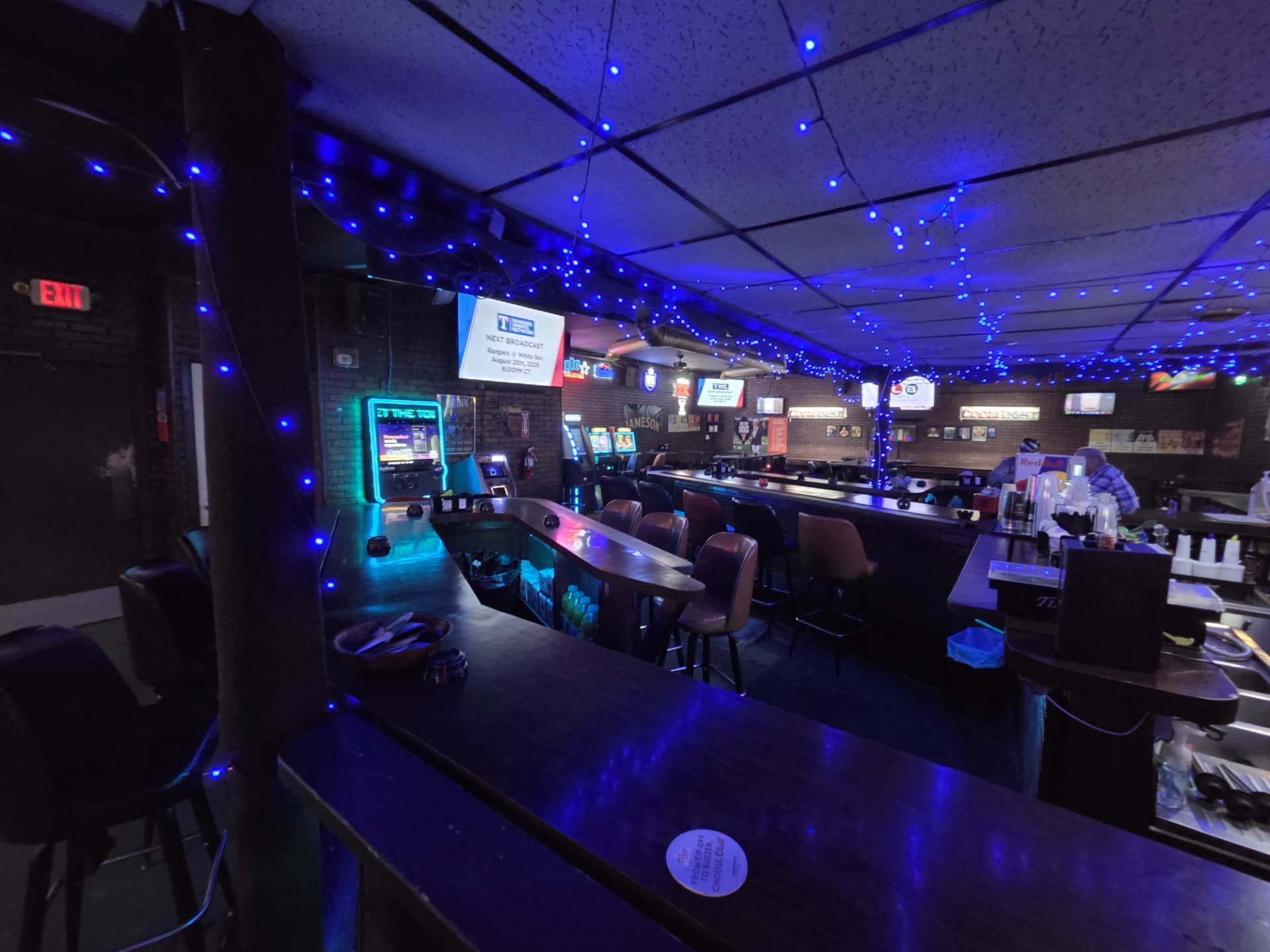 Jukebox and gaming wall glowing green and blue at the end of the bar