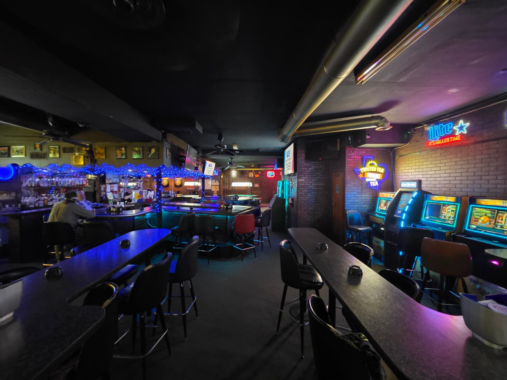 Gaming machines glowing next to high-top tables and the Miller Lite neon