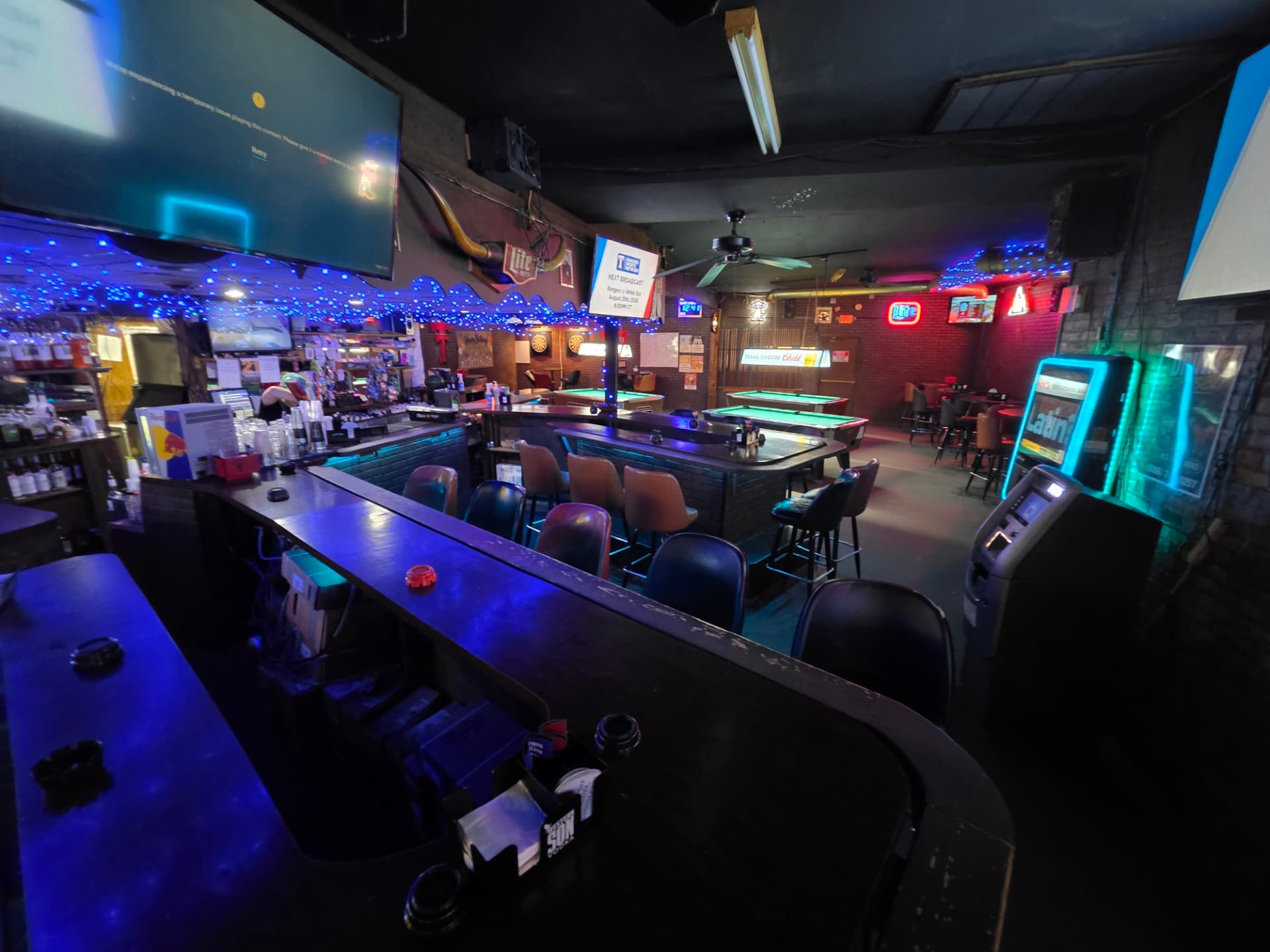 Wide view of the room: bar, ATM, pool tables and neon signs