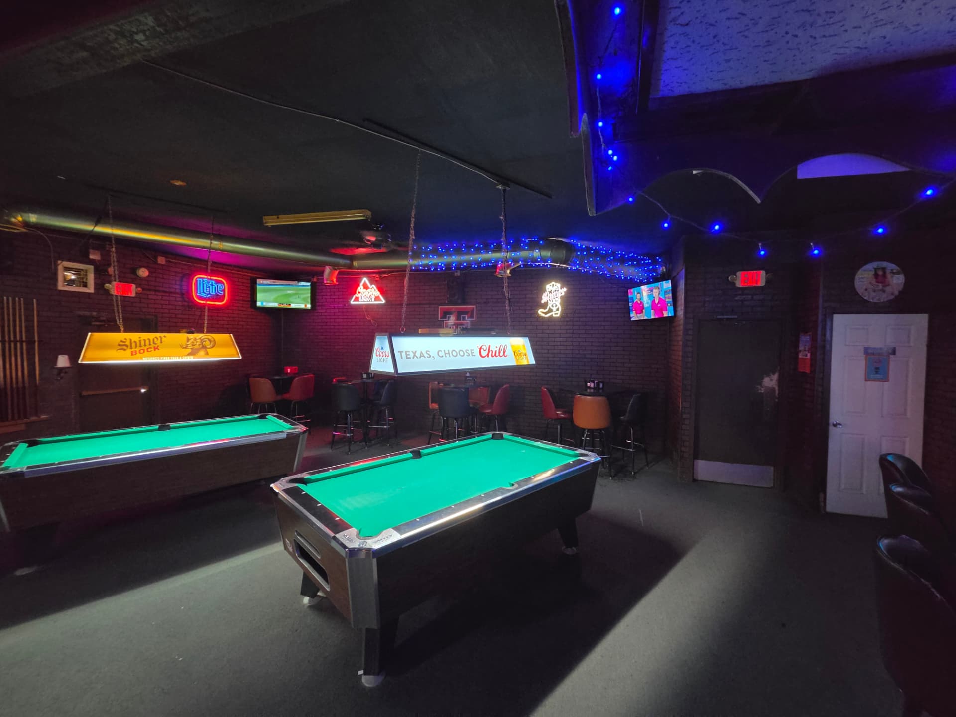 Pool room with two tables, neon beer signs and Shiner Bock lamp